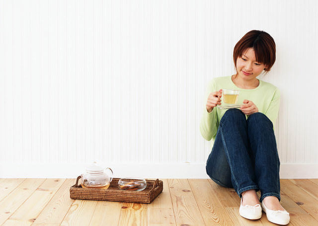 部屋の隅に座りお茶を飲む女性