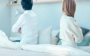 ベッドで背をむけあうカップル